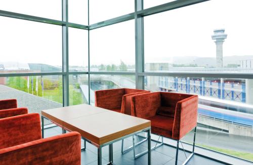 a table and chairs in a room with windows at Radisson Blu Hotel, Trondheim Airport in Stjoerdal