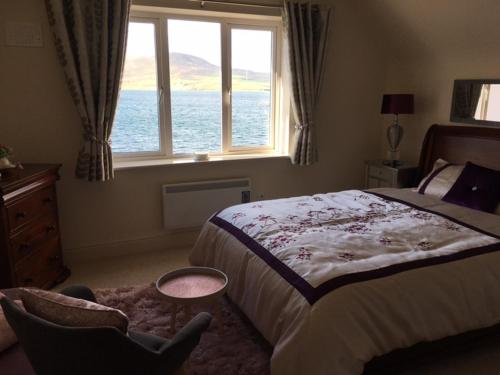 a bedroom with a bed and a window and a chair at No.21 Sandpiper's Nest Apartment in Valentia Island
