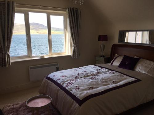 a bedroom with a bed and a large window at No.21 Sandpiper's Nest Apartment in Valentia Island