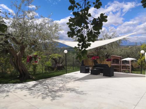 a patio with a white canopy and chairs and a tree at Lory in Elice