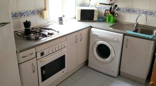 a kitchen with a stove and a washing machine at habitación muy cerca del centro, en el metro 10min a sol/ gran vía in Madrid