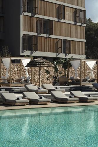 a group of lounge chairs next to a swimming pool at OKU Ibiza in San Antonio