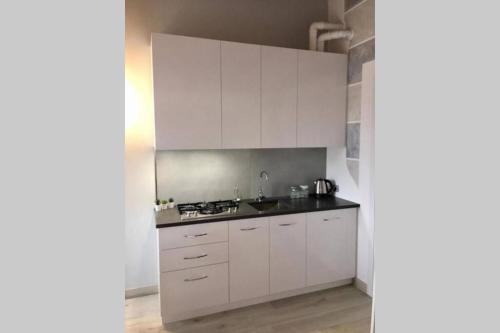 a kitchen with white cabinets and a black counter top at La petite maison de Stephanie in Clusane sul Lago