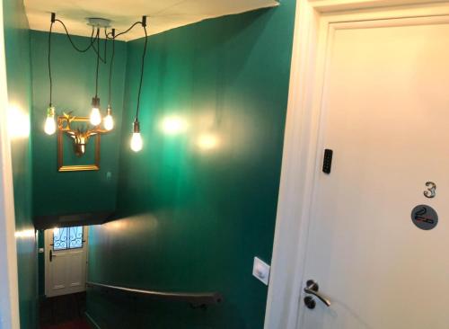 a bathroom with green walls and a chandelier at Les studios de la faisanderie in Chantilly