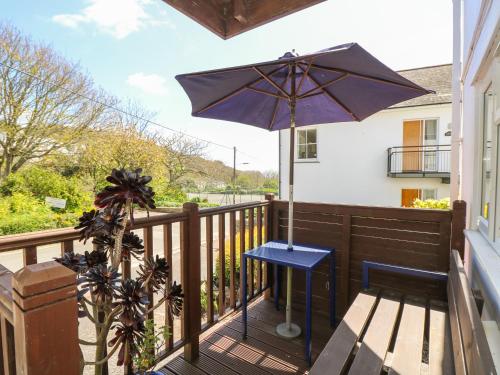 a porch with an umbrella and a blue table and bench at Seascape in Porthcurno