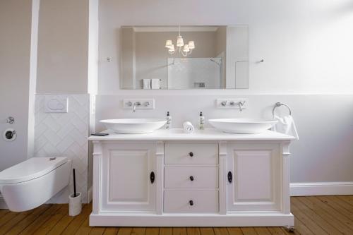La salle de bains blanche est pourvue de 2 lavabos et de toilettes. dans l'établissement Boutique Charme Apartment Ricarda, à Baden-Baden