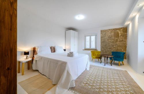 a white bedroom with a bed and a table and chairs at On the Rock Apartments in Šibenik