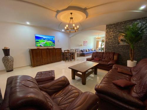 a living room with leather couches and a television at Sweet Jacob's Apartments in Fez