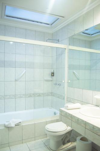 a bathroom with a tub and a toilet and a sink at Hotel Carvallo in Cuenca