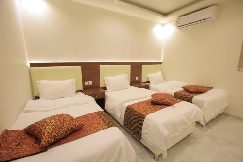 Al Qubsahにあるمنتجع جزيرة الروز بالهداの茶色の枕が付いたベッド3台が備わる客室です。