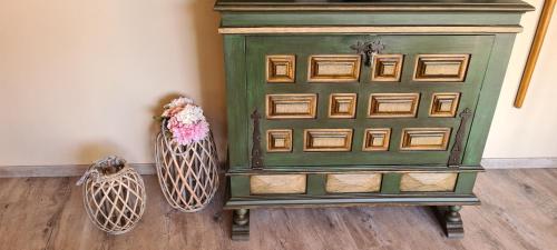 a green cabinet sitting on a wooden floor with two vases at Catavento in Porto Santo