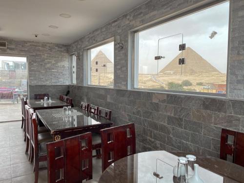 a restaurant with tables and chairs and a pyramid in the background at Best View Pyramids Hotel in Cairo