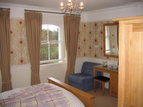 a bedroom with a bed, chair, lamp and window at Yeo Dale Hotel in Barnstaple