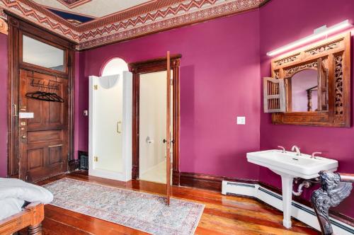 a purple bathroom with a sink and a mirror at Lumber Baron Inn and Gardens in Denver