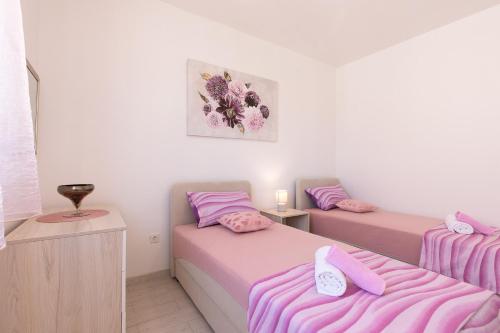 two beds in a room with pink and purple sheets at Apartment Oleander in Punat