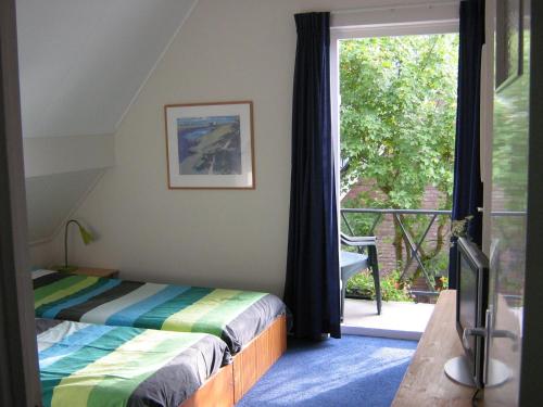 a bedroom with a bed and a large window at B&B De Esdoorn in Norg