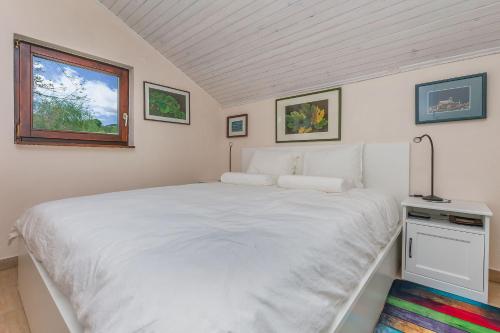un letto bianco in una stanza con finestra di House Zetna a Blato na Cetini