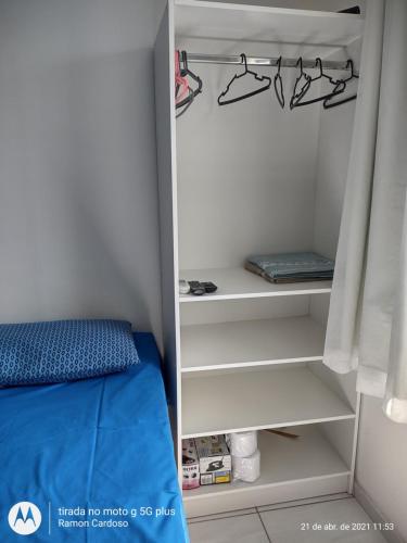 a closet with white shelves and a bed in a room at AP Praia - Vog 2 quartos com AR e D'Ouro Park-Rua dos Tangarás, 20 todo climatizado in Ilhéus
