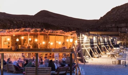 een groep mensen die in stoelen voor een gebouw zitten bij Selina Ramon in Mitzpe Ramon