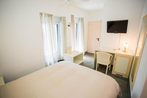 a bedroom with a bed and a desk and a tv at Hôtel du Port in Villeneuve
