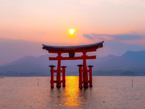 a torii gate in the water at sunset at Sotetsu Fresa Inn Hiroshima in Hiroshima