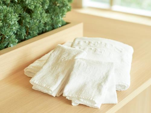 two white towels sitting on a wooden table at Sotetsu Fresa Inn Hiroshima in Hiroshima