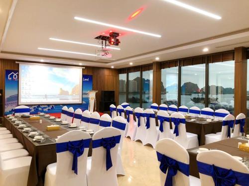 a conference room with tables and chairs and a screen at Vincent Halong Hotel in Ha Long