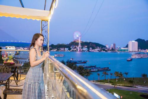a woman standing on a balcony looking at the water at Vincent Halong Hotel in Ha Long