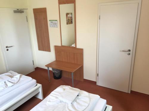 a room with two beds and a table and a mirror at Hotel Hennies Hannover Sehnde in Hannover