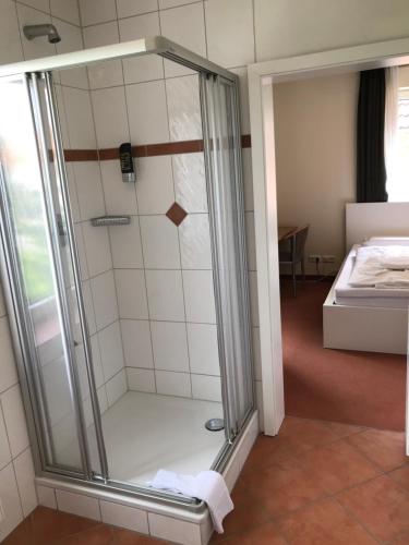 a walk in shower in a room with a bed at Hotel Hennies Hannover Sehnde in Hannover