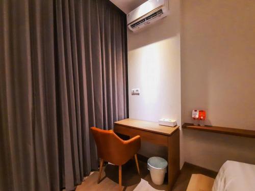 a room with a desk and a chair next to a curtain at Votel Krakatau Boutique Hotel Semarang in Semarang