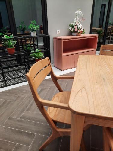 a wooden table and chairs in a room with potted plants at Votel Krakatau Boutique Hotel Semarang in Semarang