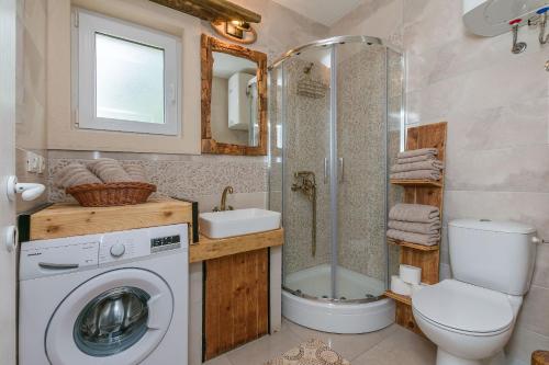 a bathroom with a shower toilet and a washing machine at House Mali dvori in Krivodol