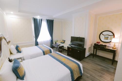 Cette chambre comprend deux lits et une télévision. dans l'établissement Vincent Halong Hotel, à Hạ Long