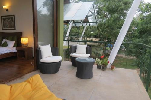 a patio with two chairs and a bed on a balcony at Waterwoods Lodge Kabini in Begūr