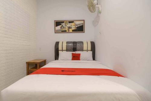 een slaapkamer met een wit bed en een rode deken bij RedDoorz @ Mutiara Residence in Pulauberayan Dadap