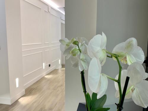 wazon z białymi kwiatami w pokoju w obiekcie Toledo Boutique Rooms w mieście Napoli
