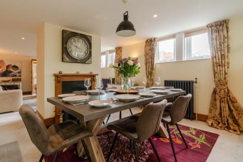 a dining room table with chairs and a clock on the wall at Old Chapel in Cheltenham