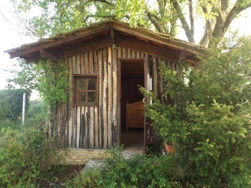 une petite cabane en bois avec une porte dans une forêt dans l'établissement Location de vacance au coeur du Périgord Noir, au Bugue