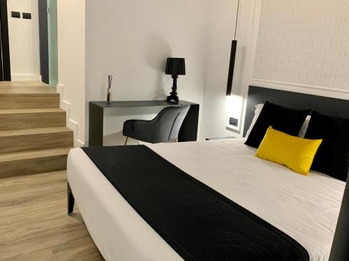 a bedroom with a bed with a yellow pillow and a desk at Toledo Boutique Rooms in Naples