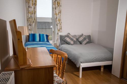 a small room with a bed and a table and chair at Beach Walk Apartment in Broughty Ferry