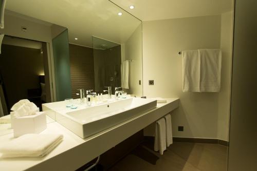 a bathroom with a large white sink and a mirror at Hôtel des Voyageurs Boutique in Lausanne