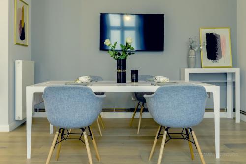 a dining room table with two blue chairs and a vase with flowers at Krosno4YOU in Krosno