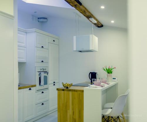 a kitchen with white cabinets and a wooden counter at Krosno4YOU in Krosno