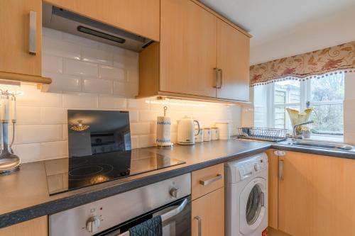 a kitchen with a stove top oven next to a washing machine at Forsythia Cottage in Bourton on the Water