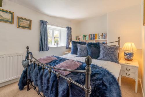 a bedroom with a bed with a blue blanket at Forsythia Cottage in Bourton on the Water