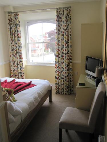 a bedroom with a bed and a chair and a window at Yeo Dale Hotel in Barnstaple