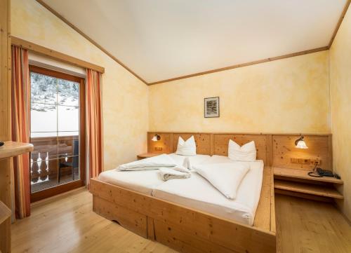 a bedroom with a large bed with white sheets and a window at Alfaierhof-Bergheimat in Gschnitz