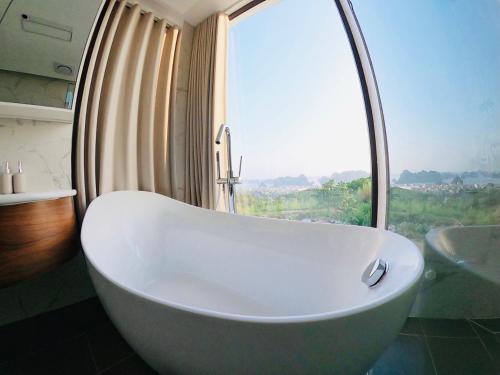 a large white tub in a bathroom with a window at FLC Villa Hạ Long 5 Phòng Ngủ in Ha Long