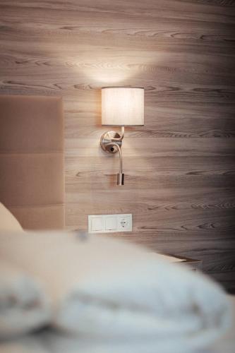 a lamp on a wall next to a bed at Hotel St-Leonhard in Sankt Leonhard im Pitztal
